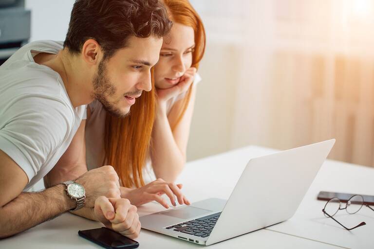 Ein Mann und eine Frau schauen gemeinsam auf einen Laptop-Bildschirm.