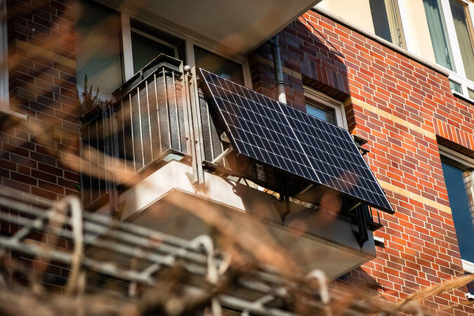 Ein Solar-Panel ist auf dem Balkon eines Backsteingebäudes montiert.