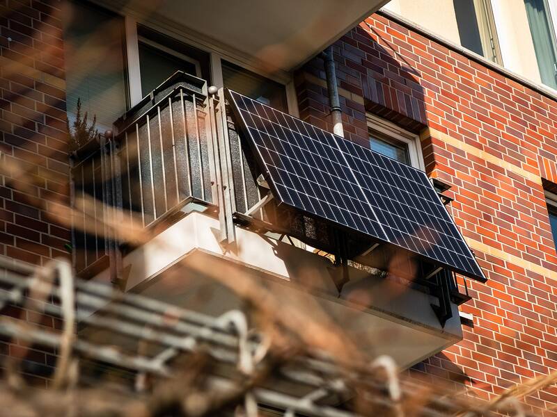 Ein Solar-Panel ist auf dem Balkon eines Backsteingebäudes montiert.