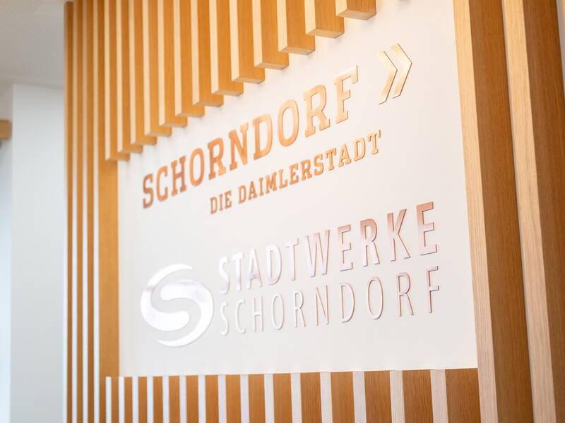 Ein Schild mit der Aufschrift "Schorndorf - Die Daimlerstadt" und "Stadtwerke Schorndorf" ist in eine moderne Holzwand integriert.